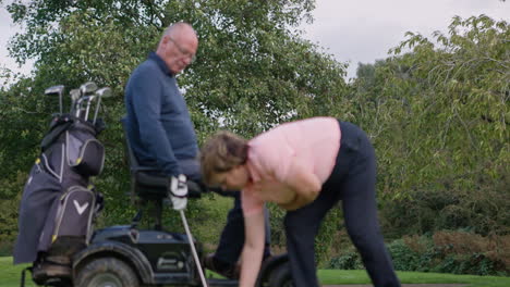 disabled golfer receives assistance on the green