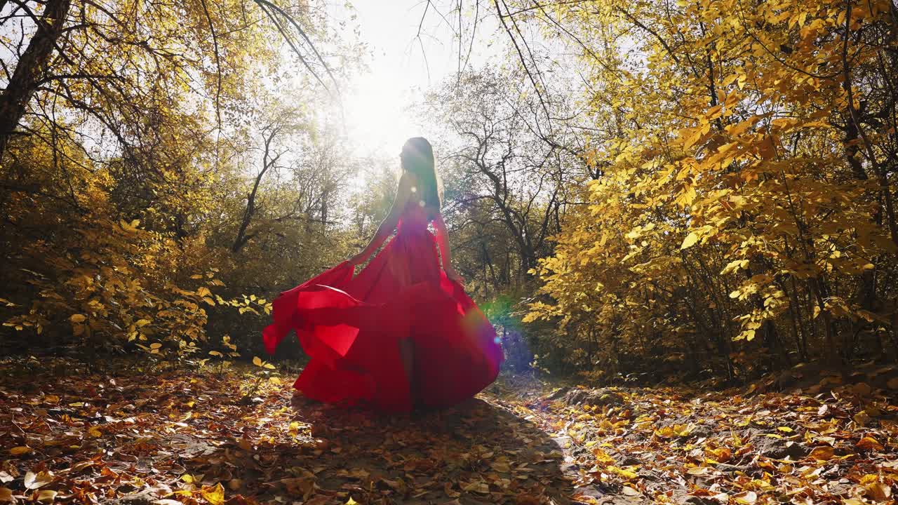 A Enchanting Scene of a Woman in a Flowy Red Dress Gracefully Wandering Through a Sunlit Autumn Forest, Surrounded by Vibrant Golden Leaves and Nature's Beauty