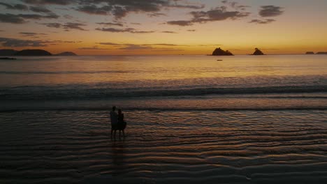 romantic couple silhouette at sunset on beach in costa rica - drone shot