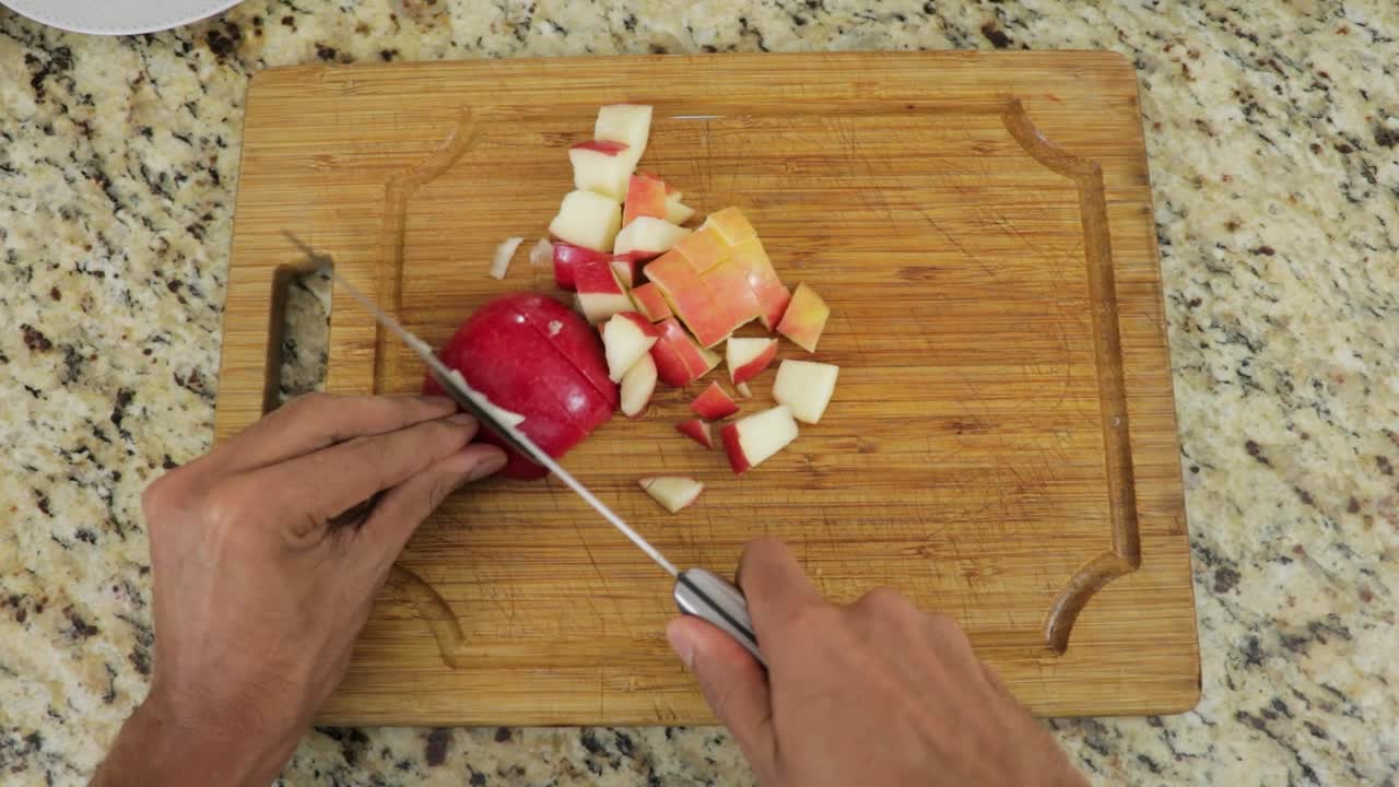 cortar la manzana de gala roja y madura en pedazos en una tabla de madera, pov disparó en las manos