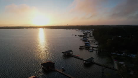 beautiful rising drone shot into the sun rising over a lake with reflection. boat docks and piers in the foreground