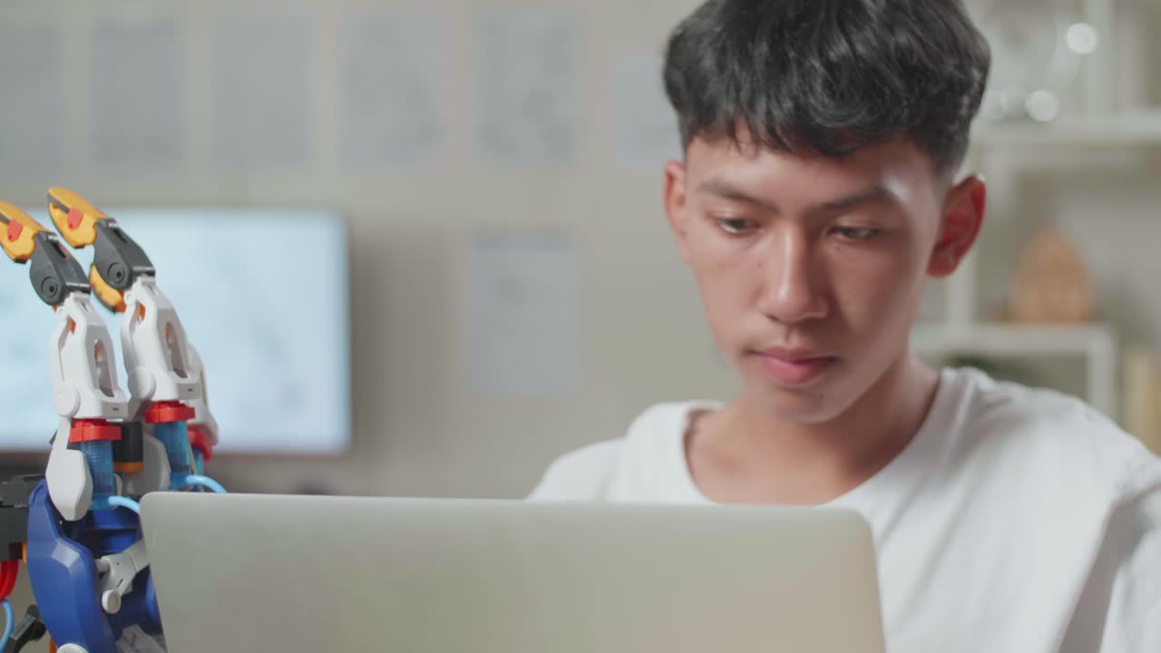 집에서 노트북에 사이보그 손을 는 동안 스트레칭하는 아시아 소년의 클로즈업