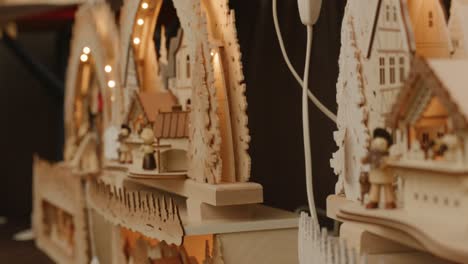 Decorative-hand-crafted-wooden-houses-with-lights-on-display-at-Balvaria-market-in-Stuttgart,-Germany,-Baden-Wurttemberg-Europe