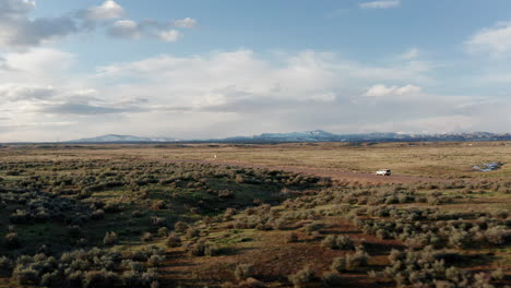 aerial tracking shot of car driving through large open idaho landscape