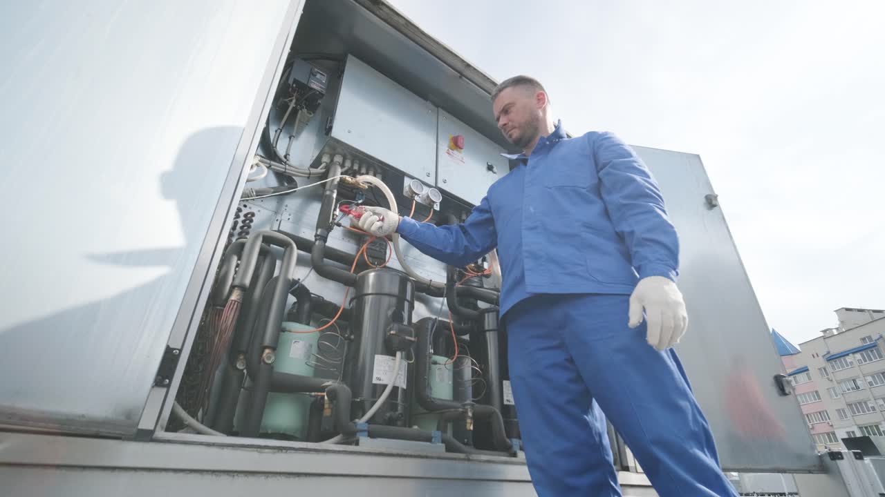 il tecnico controlla le linee elettriche dello scambiatore di calore con le pinze di corrente