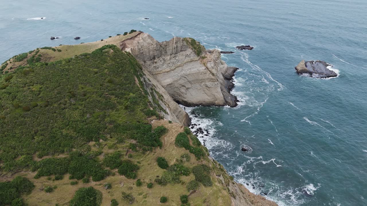 Ocean waves crashing powerfully against rugged cliffs on a cloudy day, showcasing a dramatic seascape filled with natural beauty