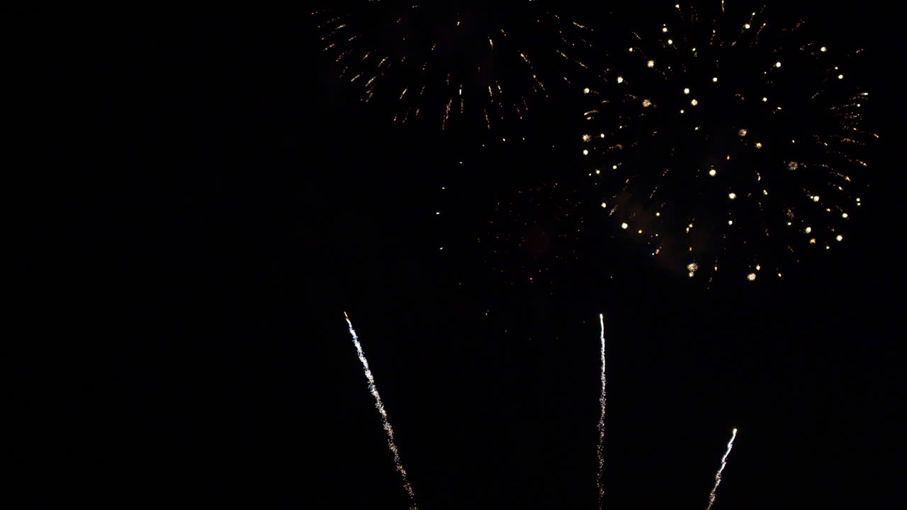 Spettacolo di fuochi d'artificio con razzi che esplodono in alto nel cielo notturno. Scintille e bagliori di materiale pirotecnico per celebrare le feste. Esplosioni di luce colorate