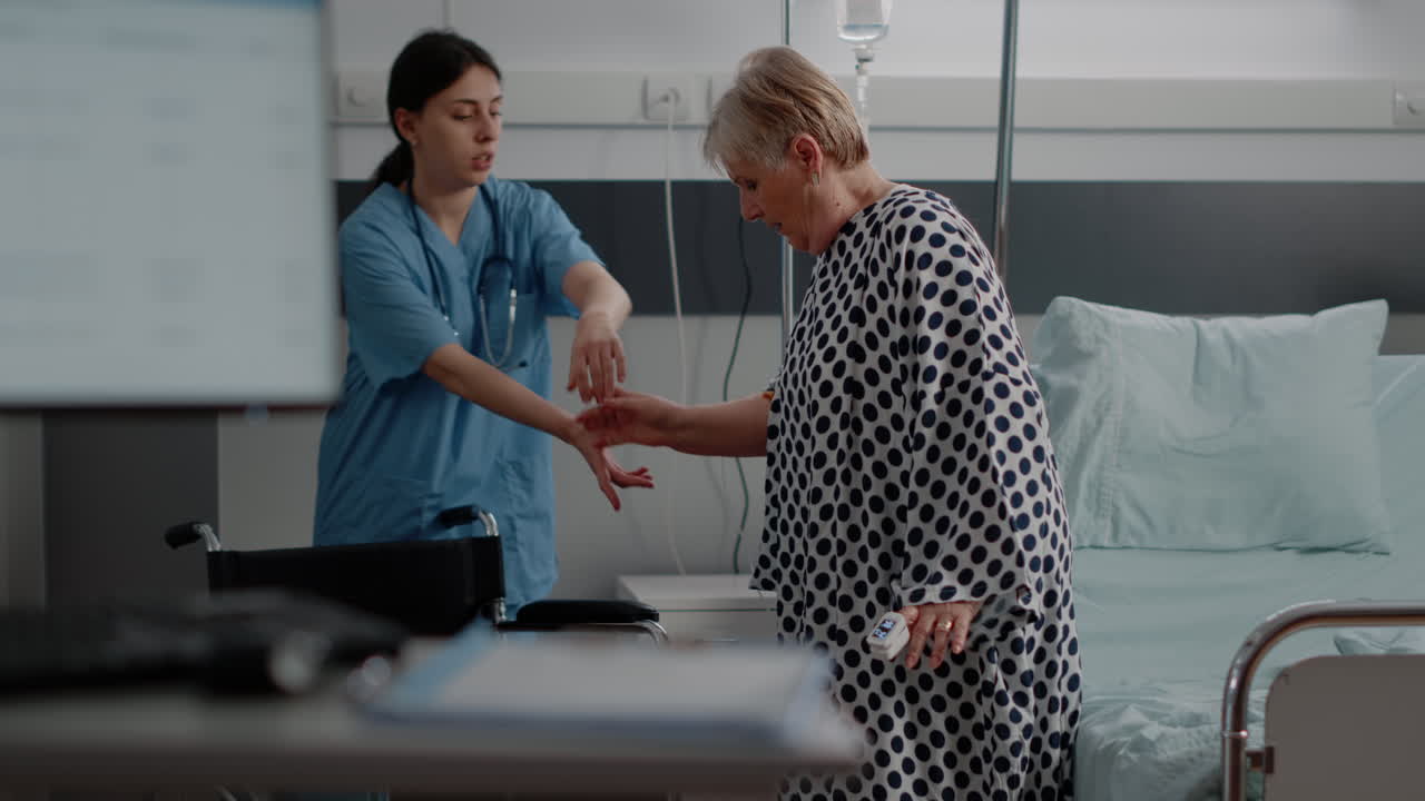 Nurse giving assistance to aged woman in hospital ward