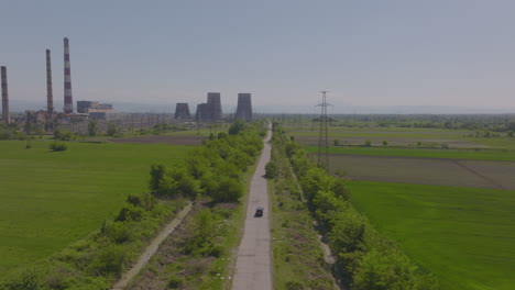 Toma-De-Carro-Hacia-Atrás-De-Un-Todoterreno-Negro-Conduciendo-Hacia-Una-Planta-De-Energía