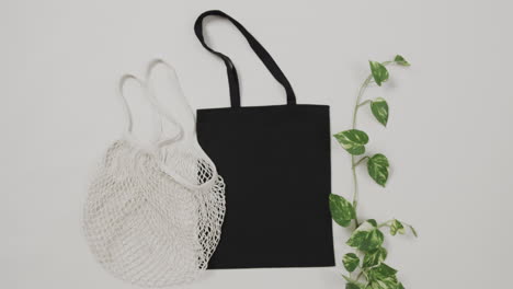 primer plano de bolsas blancas y negras con planta verde sobre fondo blanco, con espacio de copia, cámara lenta