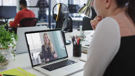 Mujer-Caucásica-Teniendo-Una-Videollamada-Con-Una-Colega-En-Una-Computadora-Portátil-En-La-Oficina