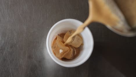 vertiendo café espresso en una taza llena de hielo