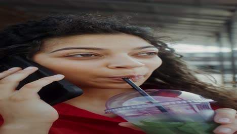 mujer joven hablando por teléfono y bebiendo una bebida