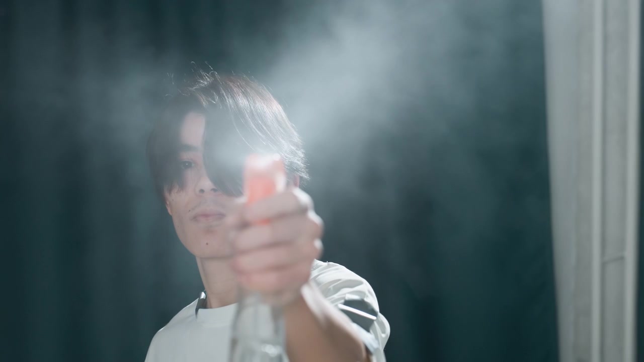 Closeup of man disinfecting with spray. Man in modern room disinfects with quick spray motion. Asian individual performing rapid disinfecting action in contemporary interior setting