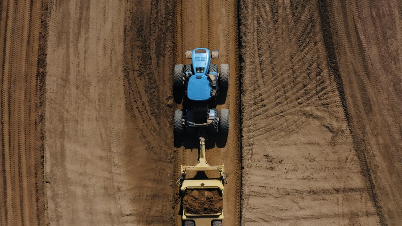 tomada aérea de un tractor que remolca cargas de tierra