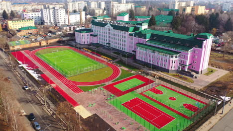 green and red stadiums near the modern building. modern outdoor fields for sports in the city. new basketball and football fields. aerial view.