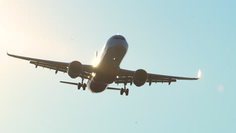 a commercial airplane approaching for landing against a clear blue sky, shot from below