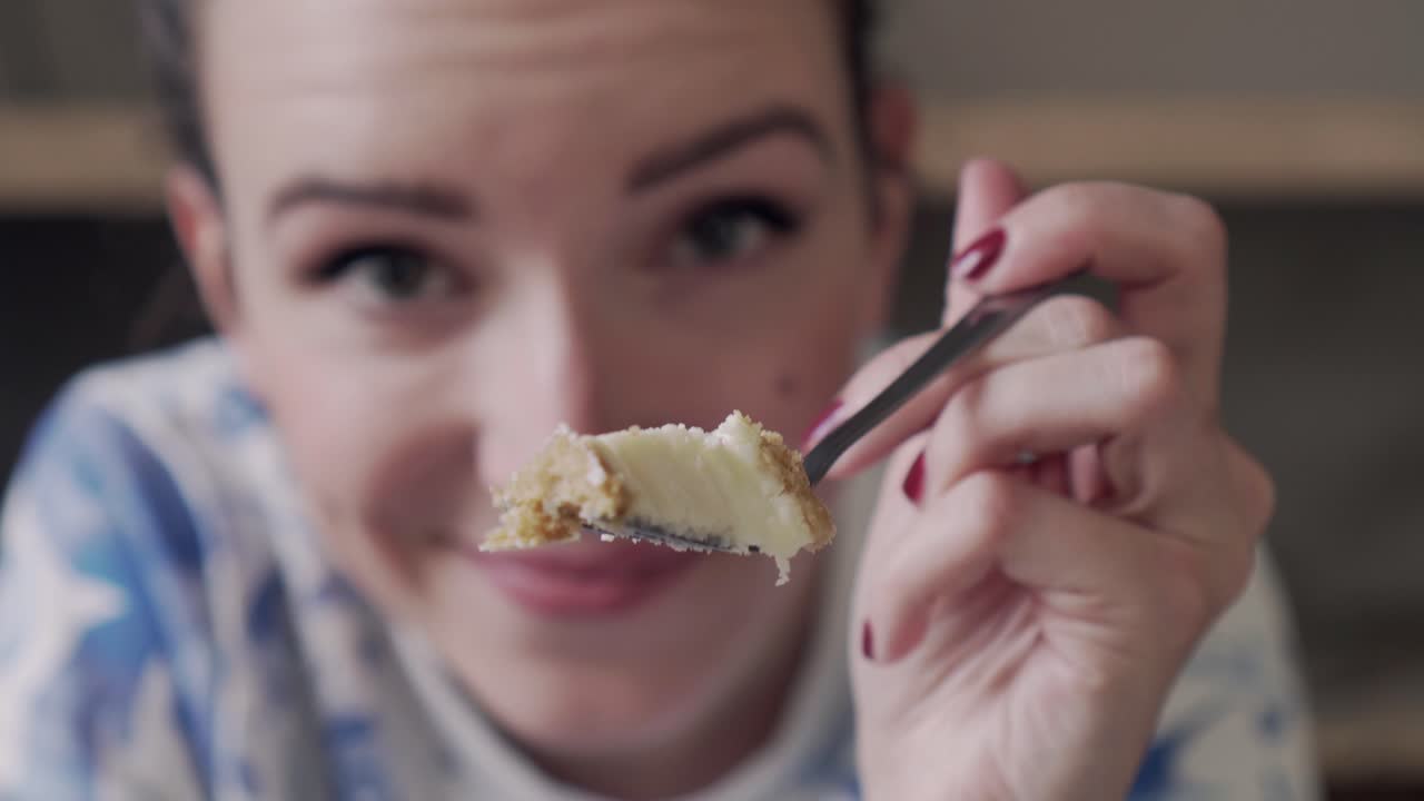 Beautiful girl is offering a piece of tasty cake with a fork