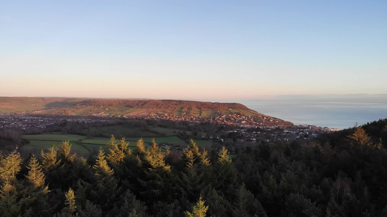 Aerial panning right shot of Sidmouth Devon at sunset with a beautiful blue sky and sea