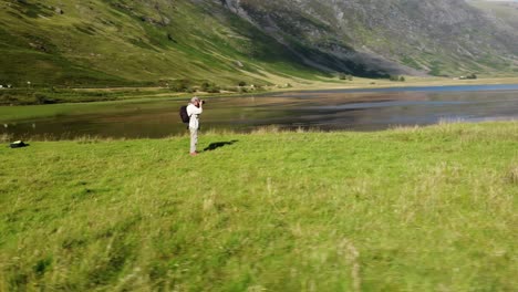 Photographer-captured-by-drone-taking-photos-in-a-green-valley