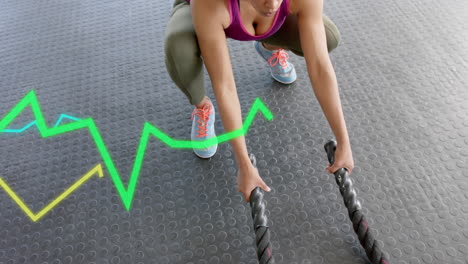 animación de datos de procesamiento de gráficos sobre mujer caucásica entrenamiento cruzado con cuerdas de batalla en el gimnasio