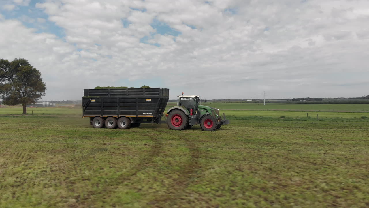 Circling follow shot around tractor pulling trailer.