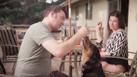 un hombre entrenando a su perro para sentarse con un pedazo de hamburguesa