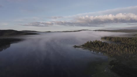 morning fog over tranquil lake reflects forest norwegian landscape drone