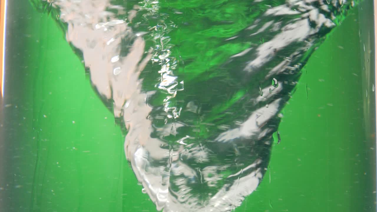 disparo estático en cámara lenta de un vórtice de agua que gira o da vueltas o un tornado de agua contra un fondo verde