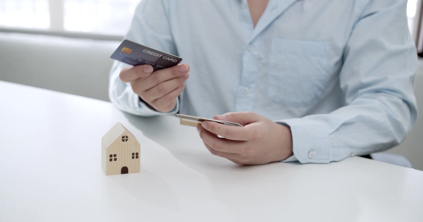 La selezione ponderata di una carta di credito da parte di un giovane per la gestione delle spese domestiche, sottolineando l'importanza della pianificazione finanziaria