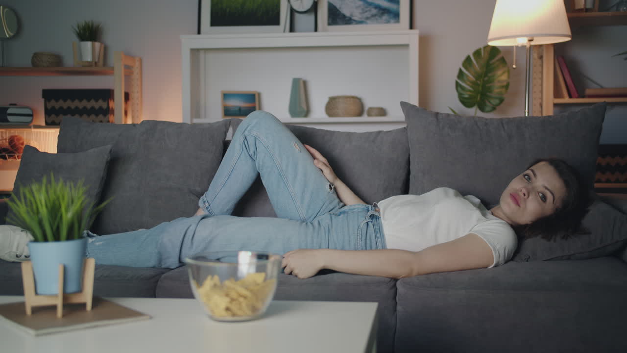 Woman Relaxing on Sofa Watching TV