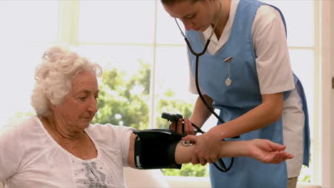 nurse taking blood pressure of senior woman