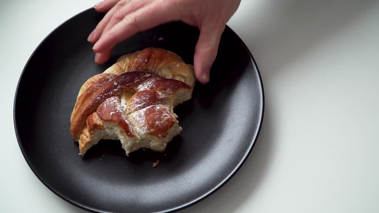 Half eaten bun on a black plate while taking a few bites