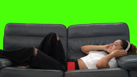 Junge-Frau-Spielt-Musik-Vom-Telefon,-Mit-Kopfhörern,-Entspannt-Auf-Der-Couch,-Greenscreen-Chroma-Key