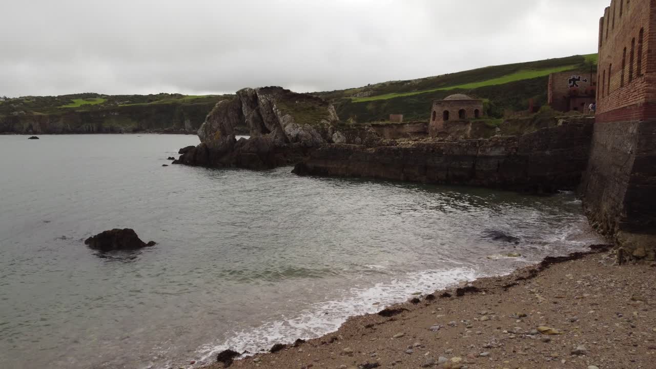 vista aérea de porth wen moviéndose hacia la fábrica de ladrillo industrial victoriana abandonada permanece en la costa erosionada de anglesey