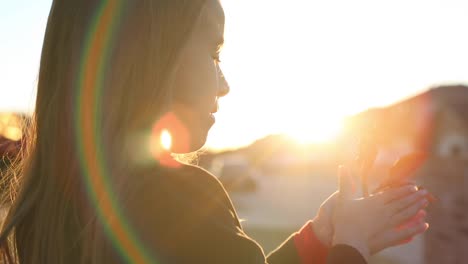 niña jugando con hojas en el sol poniente luz del sol cielo naranja y destello de lente naturaleza b roll