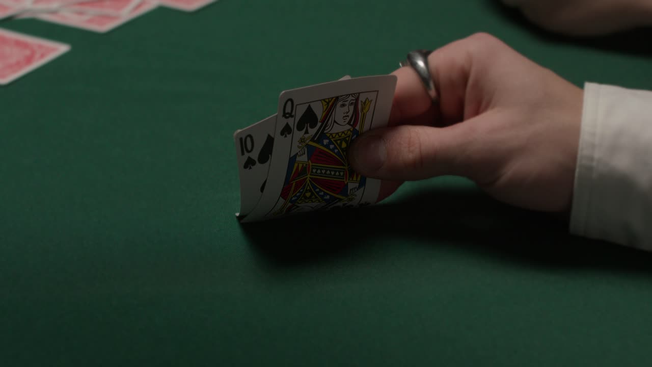 el jugador de camisa blanca saca dos cartas y las vuelve a poner en un casino oscuro