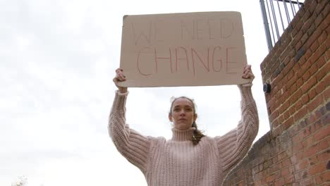 mujer fuerte de pie en protesta sosteniendo un cartel de cambio en un ángulo bajo de la calle