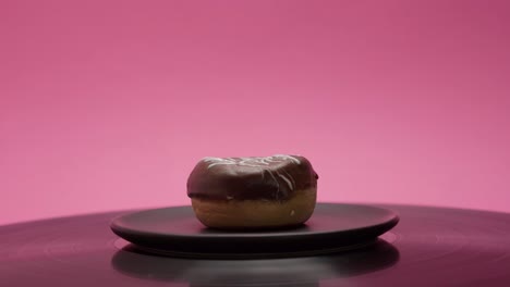 delicious black chocolate donut rolls in a circle on a pink and black background