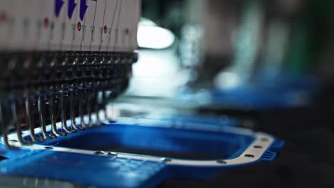 needles and threads in motion during embroidery production closeup as hoops shift and adjust to different colors, slow motion