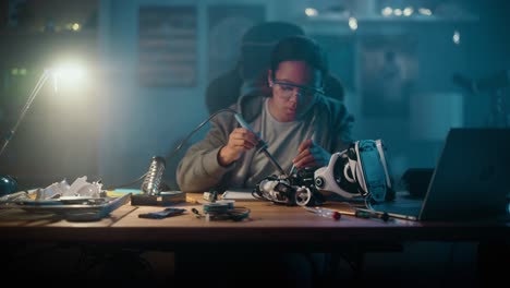 una joven adolescente multiétnica estudia electrónica y soldadura de cables y placas de circuitos en su proyecto de robótica de afición científica. una niña está trabajando en un robot en su habitación.