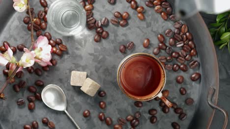 spilled coffee. a cup of coffee and a glass of water on a vintage style tray, the coffee pot breaks when pouring coffee, hot drink spills on the table. top view, 4k live video.