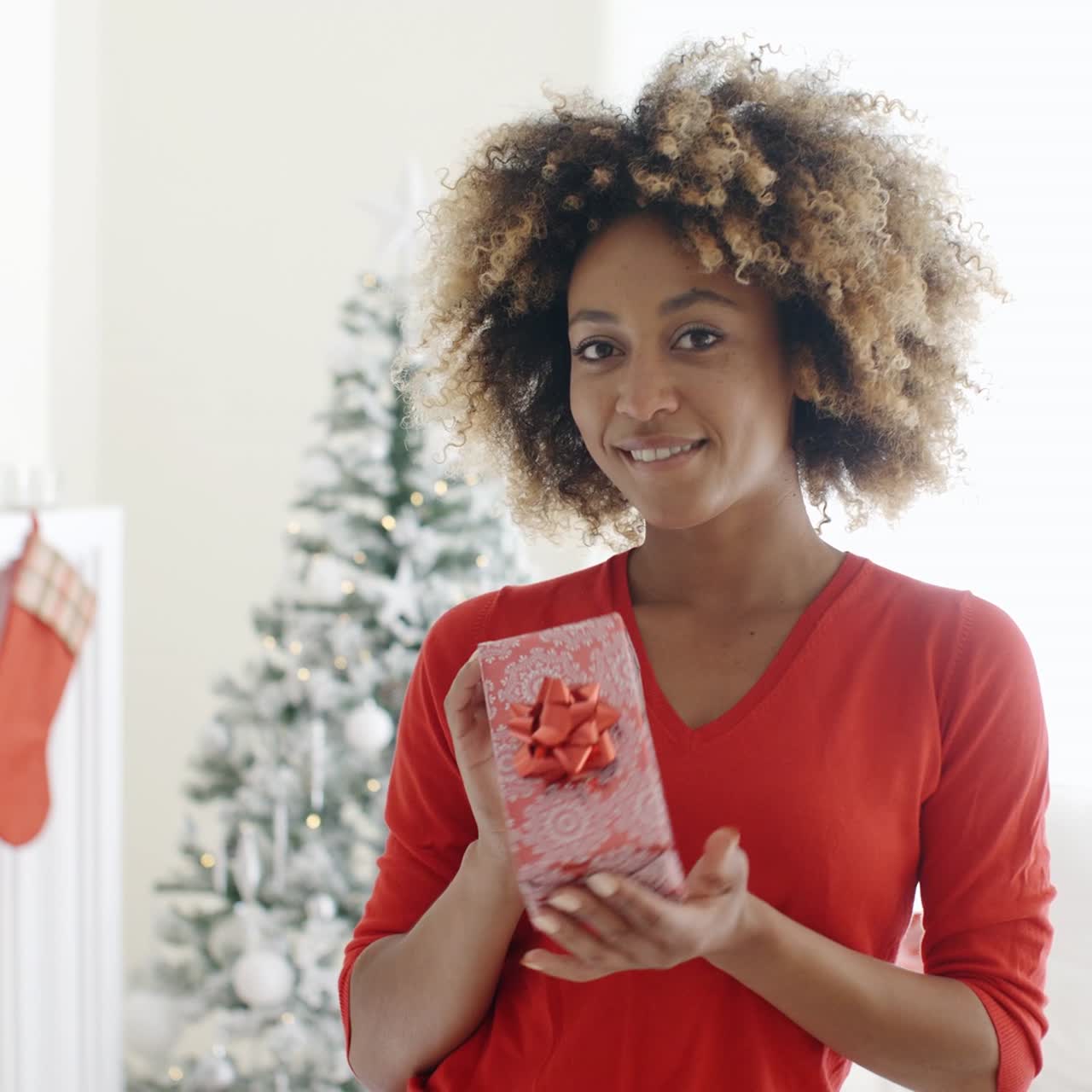 mujer sonriente sosteniendo un regalo de navidad