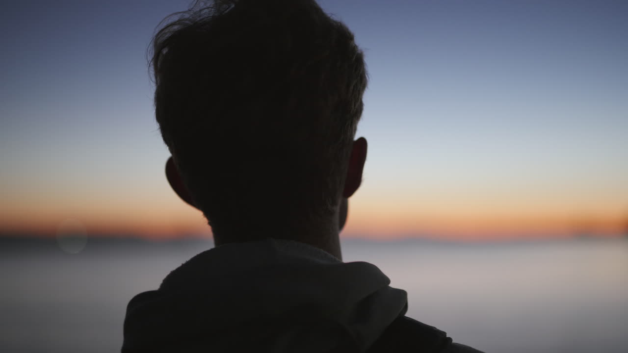 defocused 바다 일몰을 보고 사람의 머리의 후면 보기 실루엣