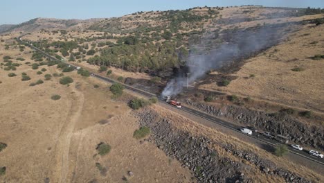 Firefighters-working-on-burning-passenger-bus-on-road-and-stopped-traffic,-drone