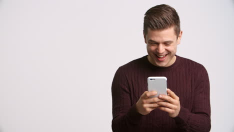 Foto-De-Estudio-De-Un-Hombre-Mirando-Un-Mensaje-De-Texto-En-Cámara-Lenta