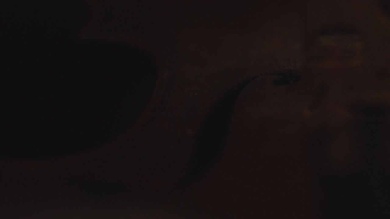 primer plano de violín antiguo, cambios de luz dramáticos sobre el instrumento, secuencias de video de música sinfónica clásica