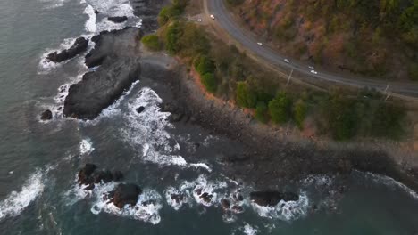 Steady-aerial-shot-of-a-two-lane-road-parallel-with-the-Pacific-coast-at-dusk,-Costa-Rica