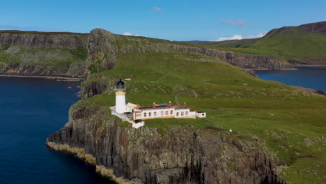 rotating drone shot of neist point lighthouse and rocky shoreline cliffs in scotland