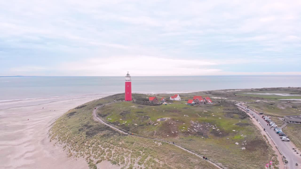 Dronebillede af Texel-fyrtårnet i Holland, omgivet af klitter, røde huse og havudsigt